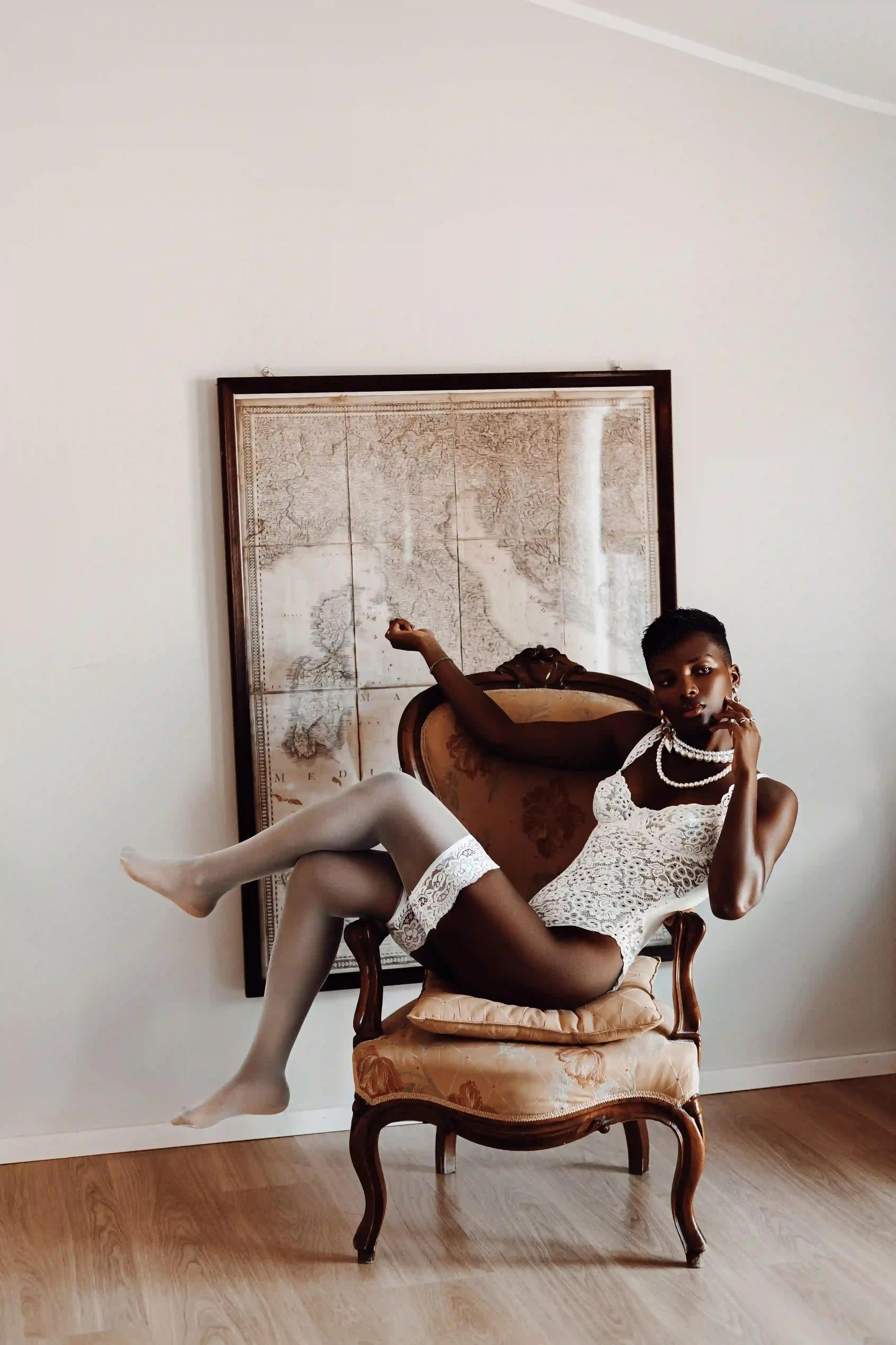 Model in white lingerie lying on an armchair with a map of Italy behind her