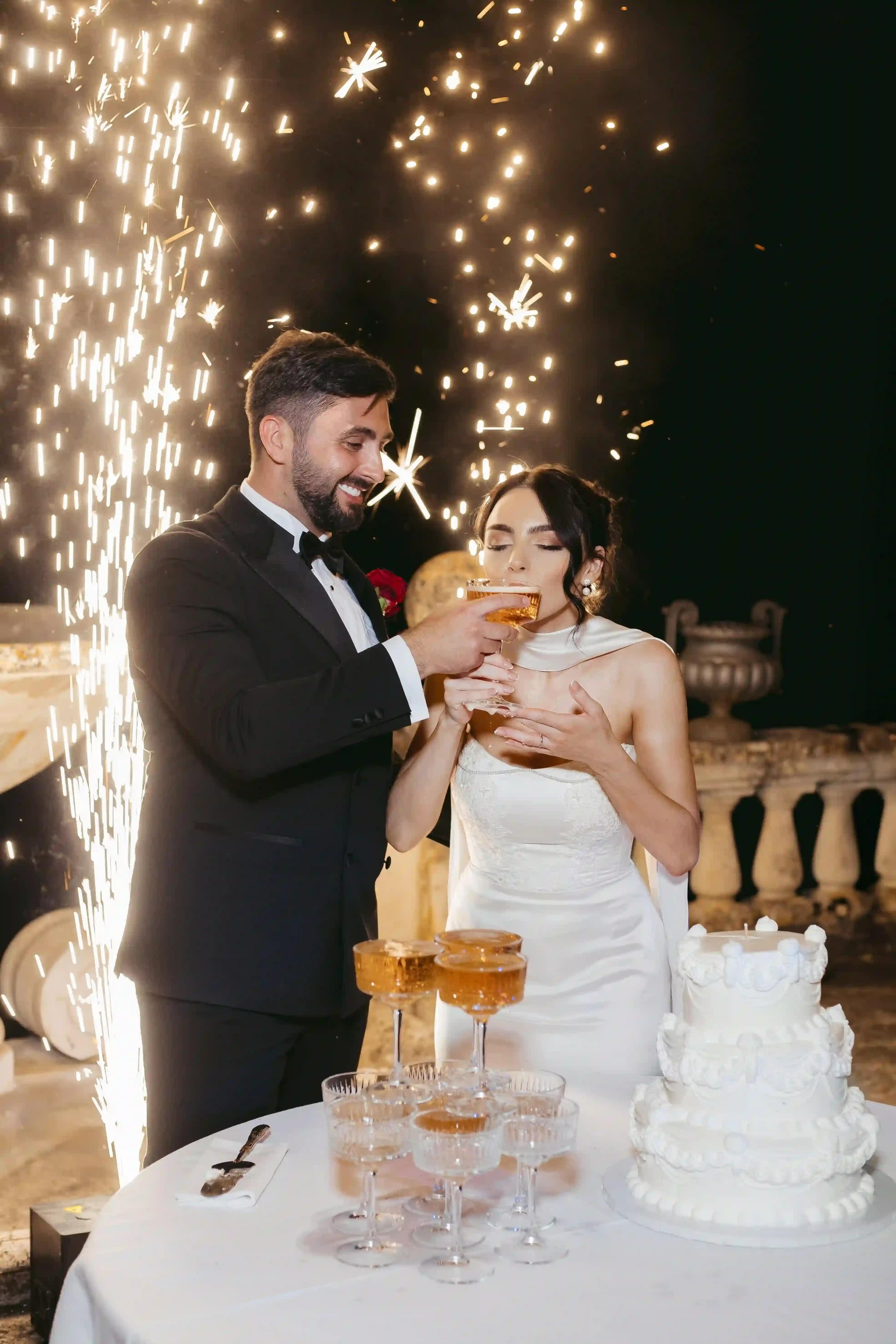 newlyweds in front of the cake with fireworks display